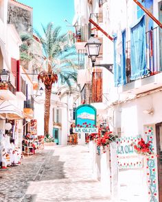 a narrow street with shops and palm trees