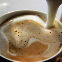 someone is pouring milk into a cup of coffee