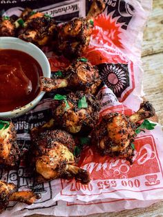 grilled chicken wings and dipping sauce on a napkin with paper wrapper around it