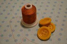 two spools of thread sitting on top of a table next to some buttons