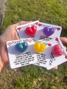 four small heart shaped magnets are held in someone's hand