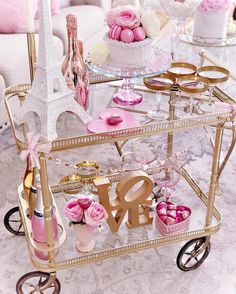 a cart filled with lots of pink and gold items sitting on top of a table