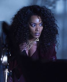 a woman with long curly hair standing in front of a mirror