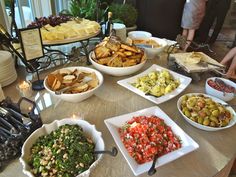 a table filled with lots of different types of food on top of plates and serving utensils