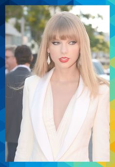 taylor swift is wearing a white suit and red lipstick in front of a group of people