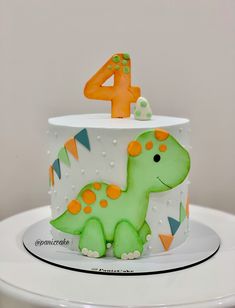 a green dinosaur cake with the number four on top