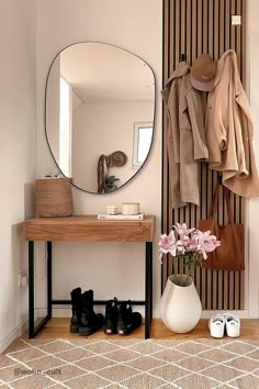 a room with a mirror, coat rack and shoes on the floor in front of it