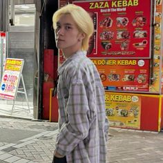 a young man with blonde hair walking down the street