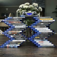 a vase filled with white flowers sitting on top of a pile of blue and white books