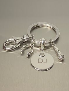 a metal keychain with two keys and a disc that says dj on it