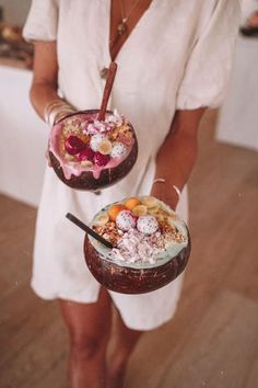 the woman is holding two desserts in their hands