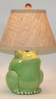 a green ceramic frog lamp with a beige shade