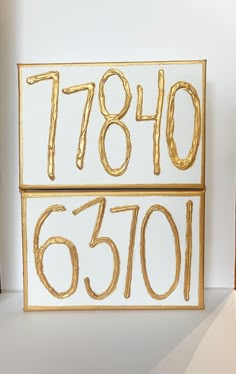 two gold foiled numbers are displayed on a white surface next to bottles and vases