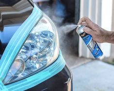 a man is cleaning the hood of a car with a blue spray bottle on it