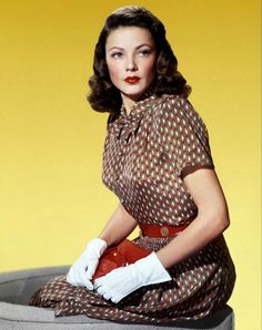 a woman sitting on top of a cement block wearing gloves and a polka dot dress