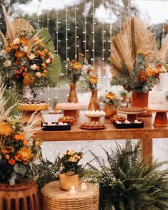 a table topped with lots of desserts next to tall planters filled with flowers