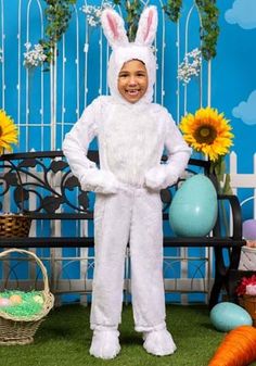 a boy in bunny suit standing next to a bench with sunflowers on it