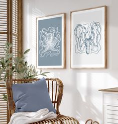 two framed pictures hang on the wall next to a wicker chair with blue pillows