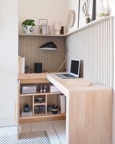 a laptop computer sitting on top of a wooden desk next to a shelf filled with books