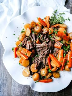 a white plate topped with roast, potatoes and carrots