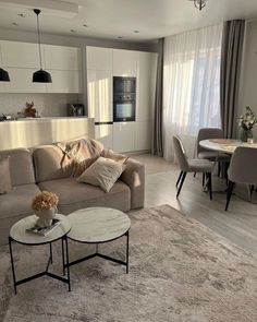 a living room filled with furniture next to a dining room table and chairs on top of a rug