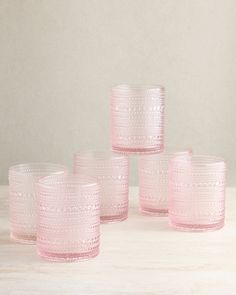 four pink glass cups sitting on top of a table