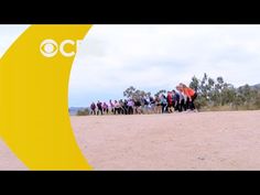 a group of people standing on top of a dirt field next to a yellow banana