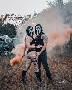 two people with painted faces hugging in a field