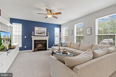 a living room with blue walls and white furniture in front of a flat screen tv