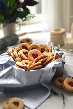 a bowl filled with heart shaped cookies sitting on top of a white tablecloth covered table