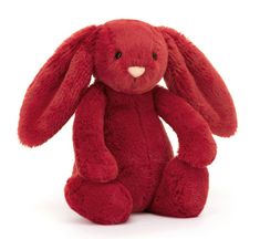 a red stuffed rabbit sitting up against a white background