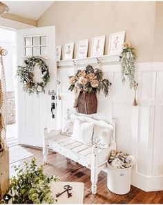 a white bench sitting in the middle of a living room filled with flowers and wreaths