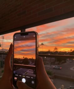 someone is taking a photo with their cell phone at sunset or sunrise over a parking lot