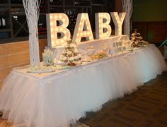 a baby sign on top of a table covered in white tulle skirted skirts