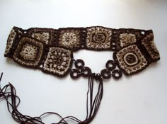 a crocheted brown and white scarf with fringes on the end is sitting on a table