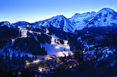 snow covered mountains and trees with lights on them