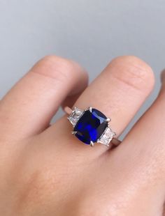 a woman's hand with a blue and white diamond ring on her left hand