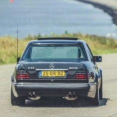 the rear end of a mercedes benz s - class car driving on a road near water