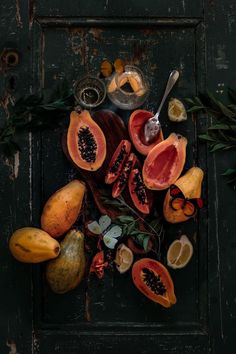 various fruits and vegetables are arranged on a wooden surface with leaves, spoons and spices