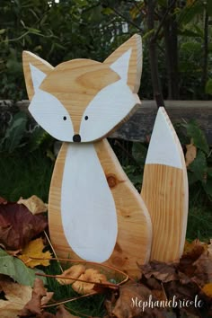 a wooden fox sitting on top of leaves