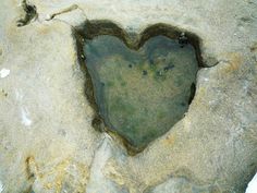 a heart shaped hole in the rock with water inside