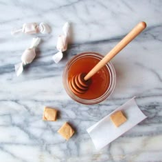 a jar of peanut butter and marshmallows on a marble table with a wooden spoon