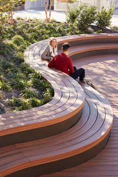 two people sitting on the edge of a curved bench