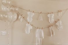 baby clothes hanging on a line with balloons in the background