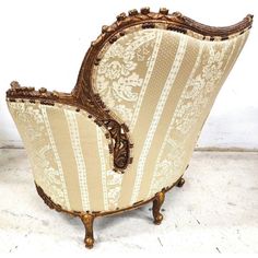 an old fashioned chair is upholstered with gold and white fabric on the back