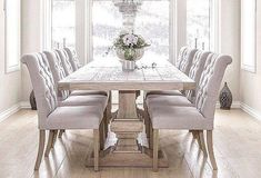 a dining room table with chairs around it and a vase full of flowers in the center