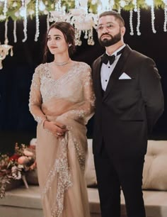 a man and woman standing next to each other in formal wear, dressed in tuxedos