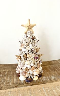 a small christmas tree made out of seashells and starfish on a wooden table