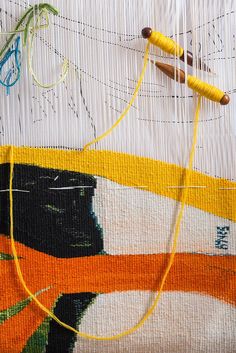 two yellow needles are hooked up to some thread on a piece of fabric that has been woven