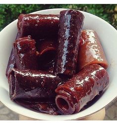 a white bowl filled with hot dogs covered in ketchup